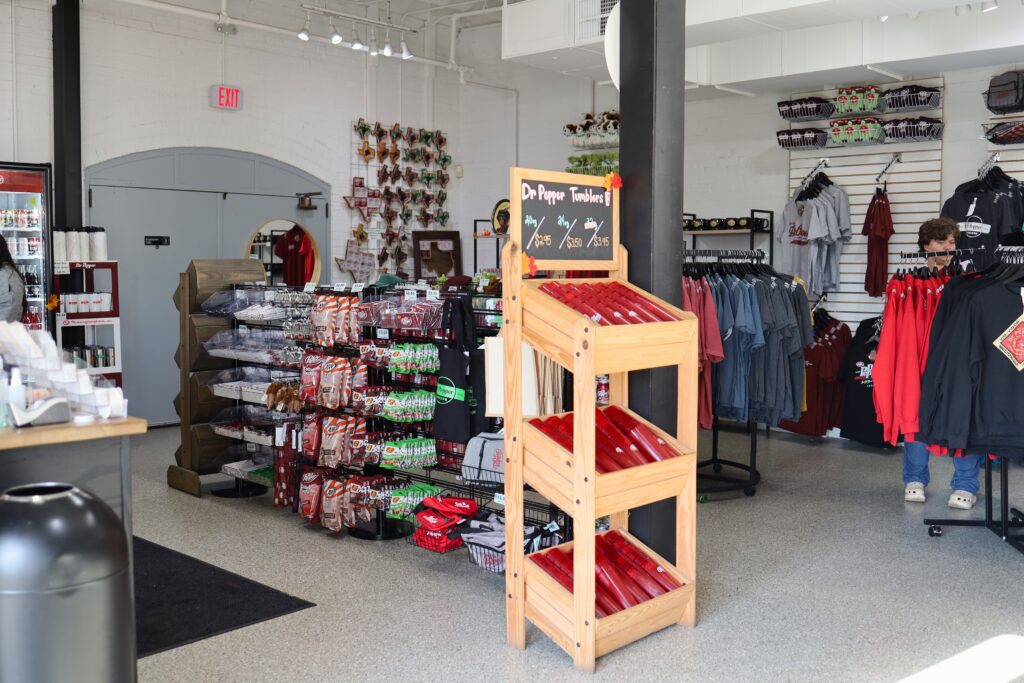 Interior of museum gift shop. Includes souvenirs such as Dr Pepper tumblers, shirts and hoodies, and candy.
